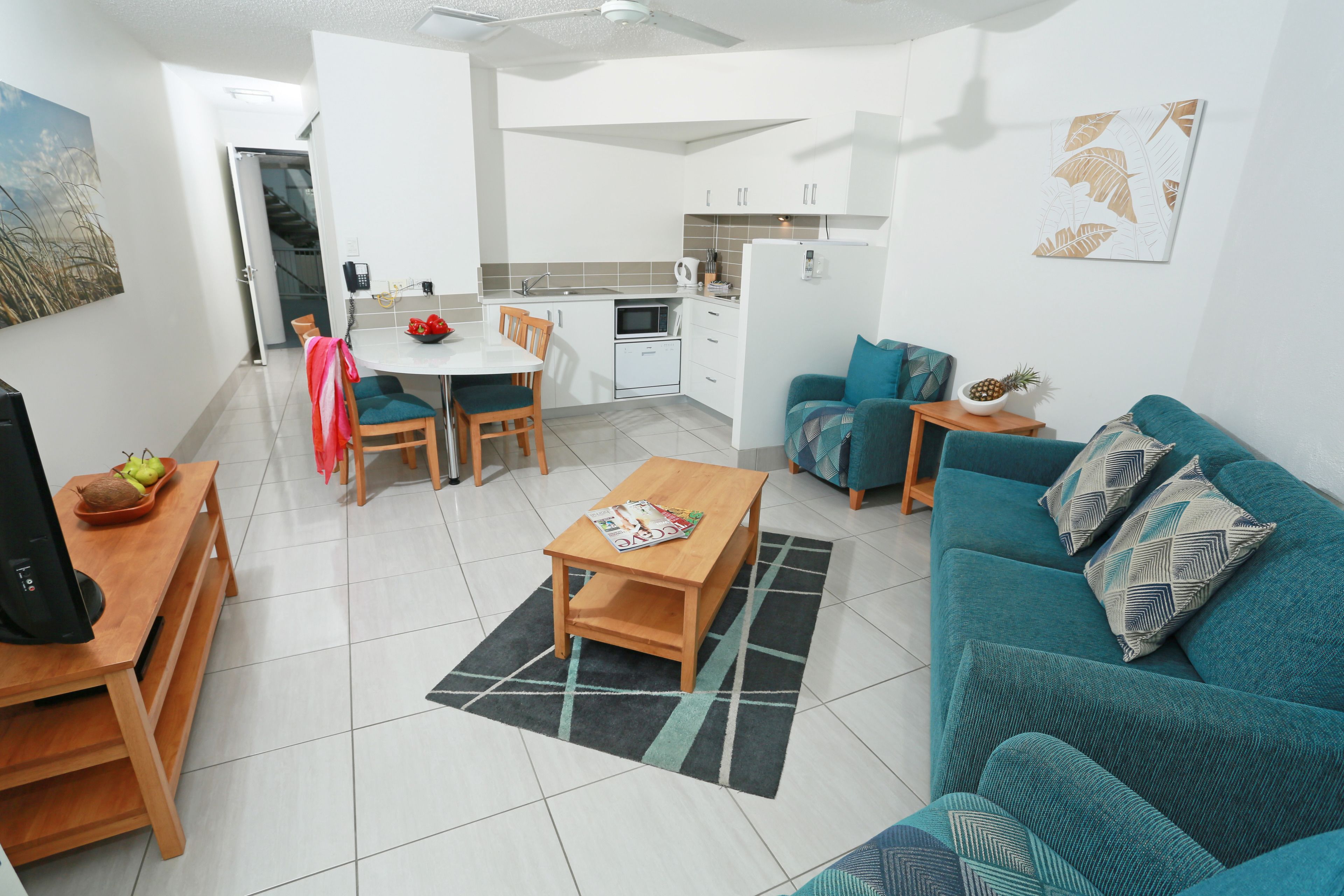 Een ruimtelijke leefruimte met eethoek, kitchenette en een bank.