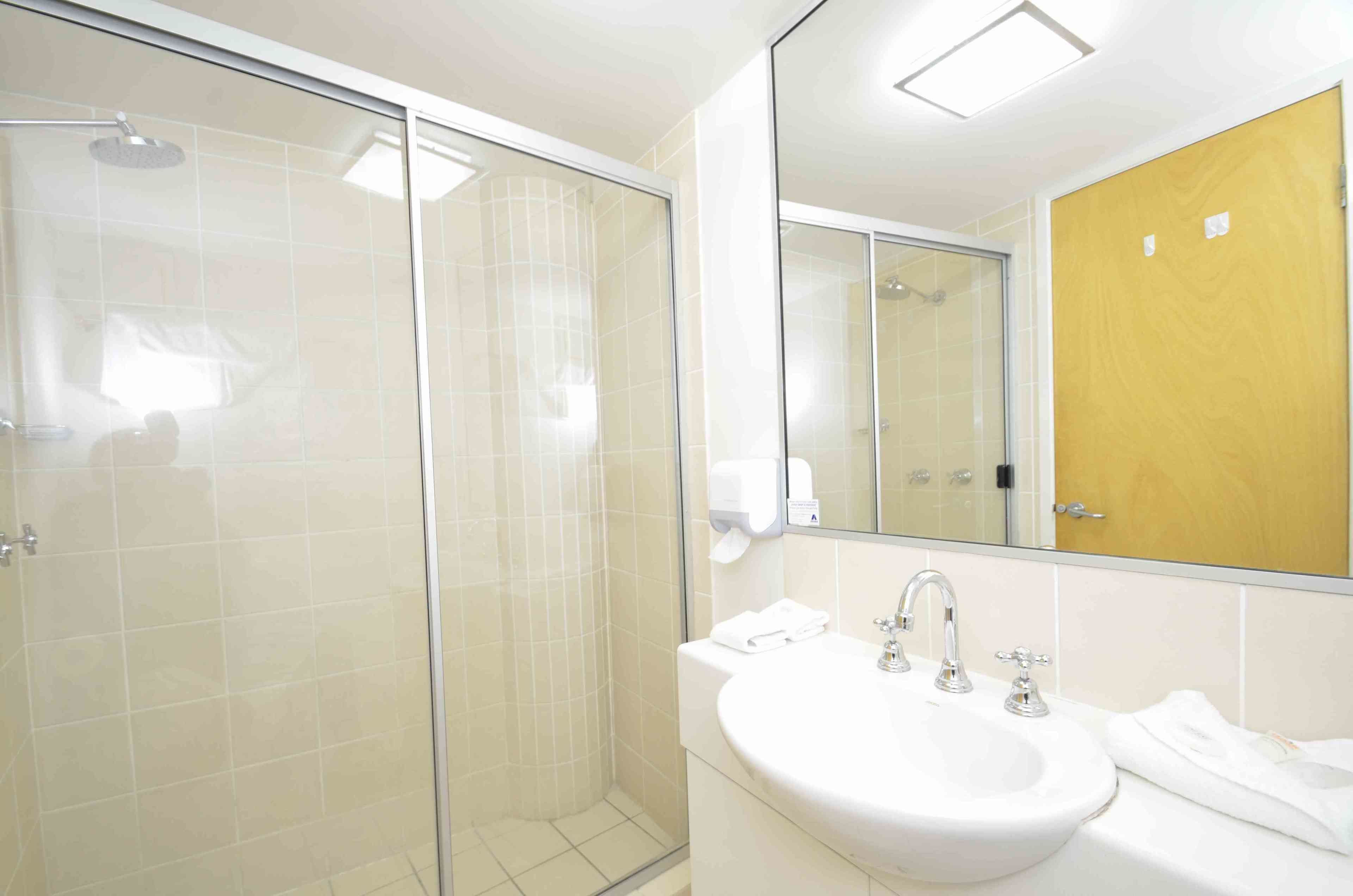 Un bagno moderno con doccia vetrata, un ampio specchio e un lavandino bianco.