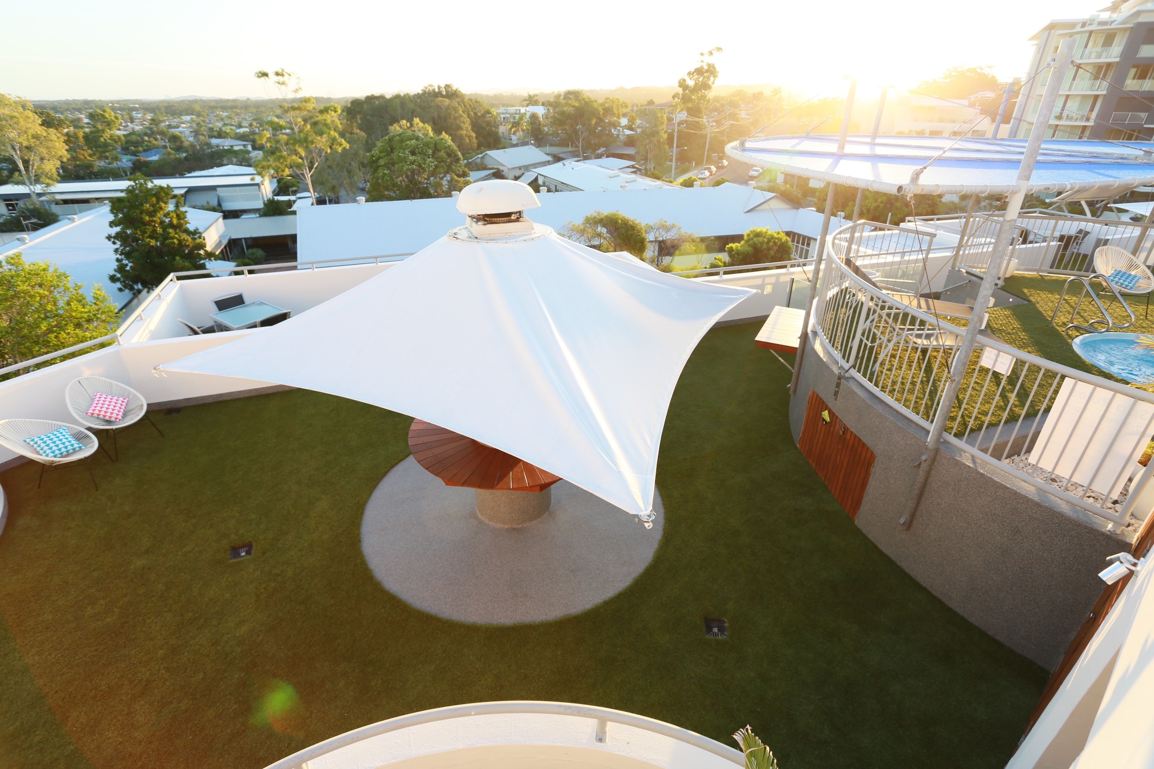 Une terrasse sur le toit, agrémentée d’un parasol blanc, d’un espace salon et offrant une vue sur les bâtiments environnants.