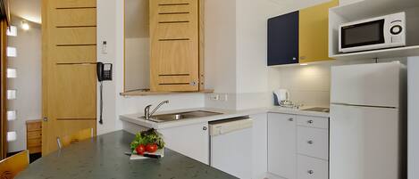 Una cocina con microondas integrado, un lavamanos y armarios de madera.