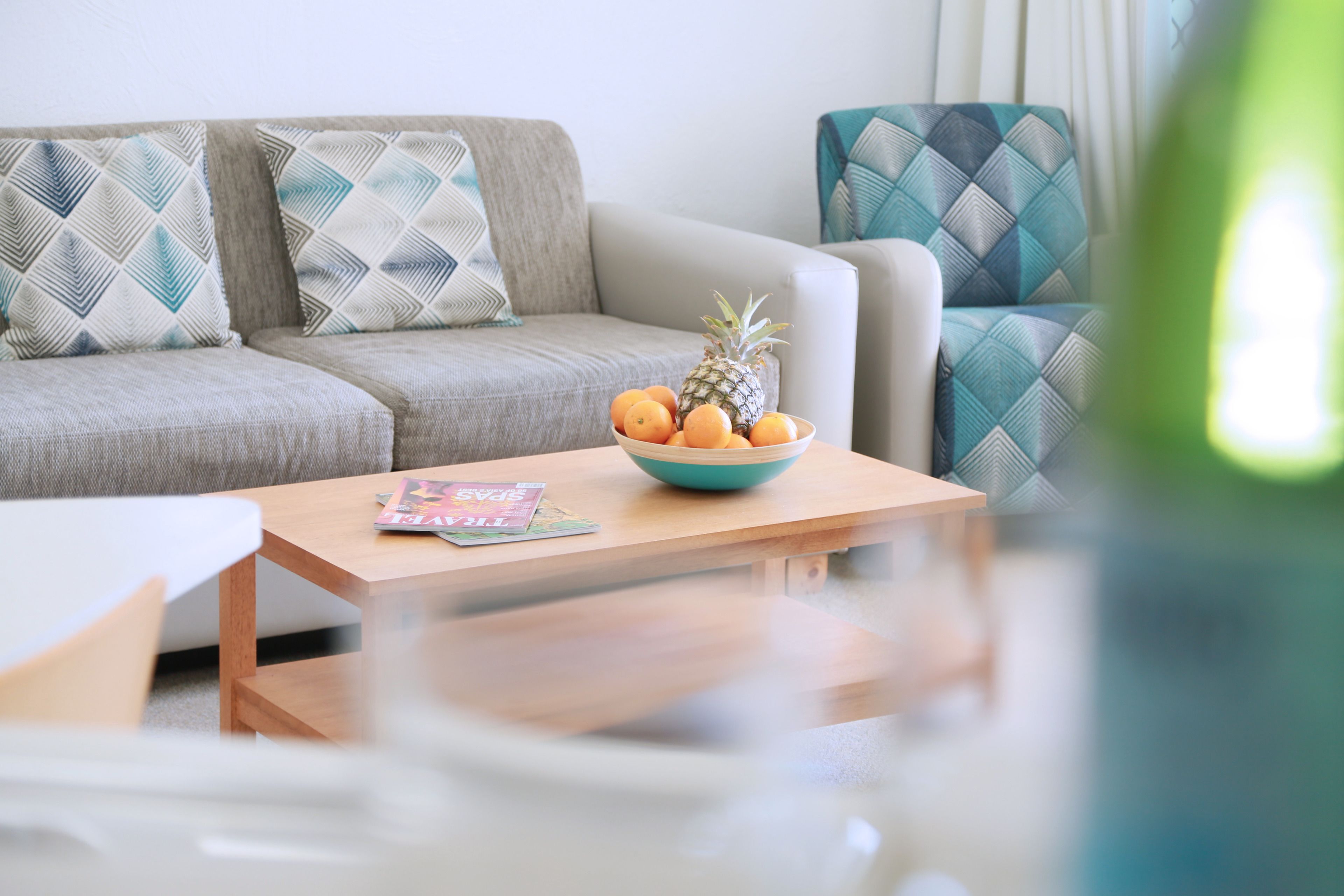 A modern living room with a sofa, a coffee table, and a bowl of fruit.