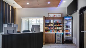 A reception area with a counter, a sign reading 'P.S. I LOVE YOU', and a refrigerator stocked with beverages.