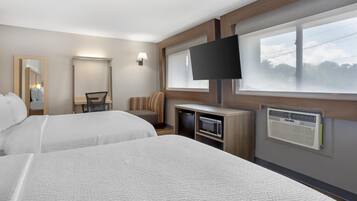 A hotel room with two beds, a desk, a chair, a flat-screen TV, and a window with blinds.