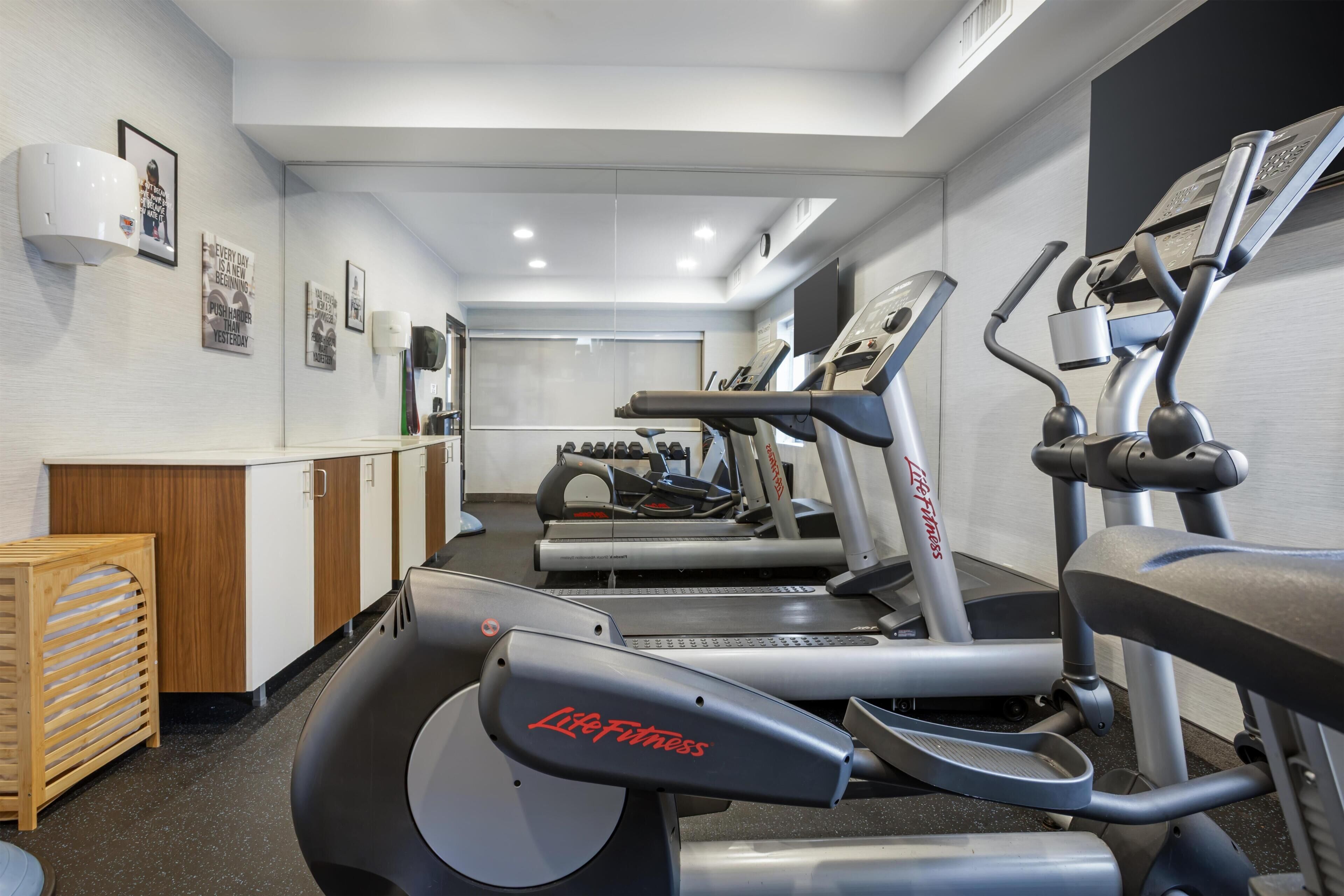 A gym with treadmills, stationary bikes, and a weight bench.