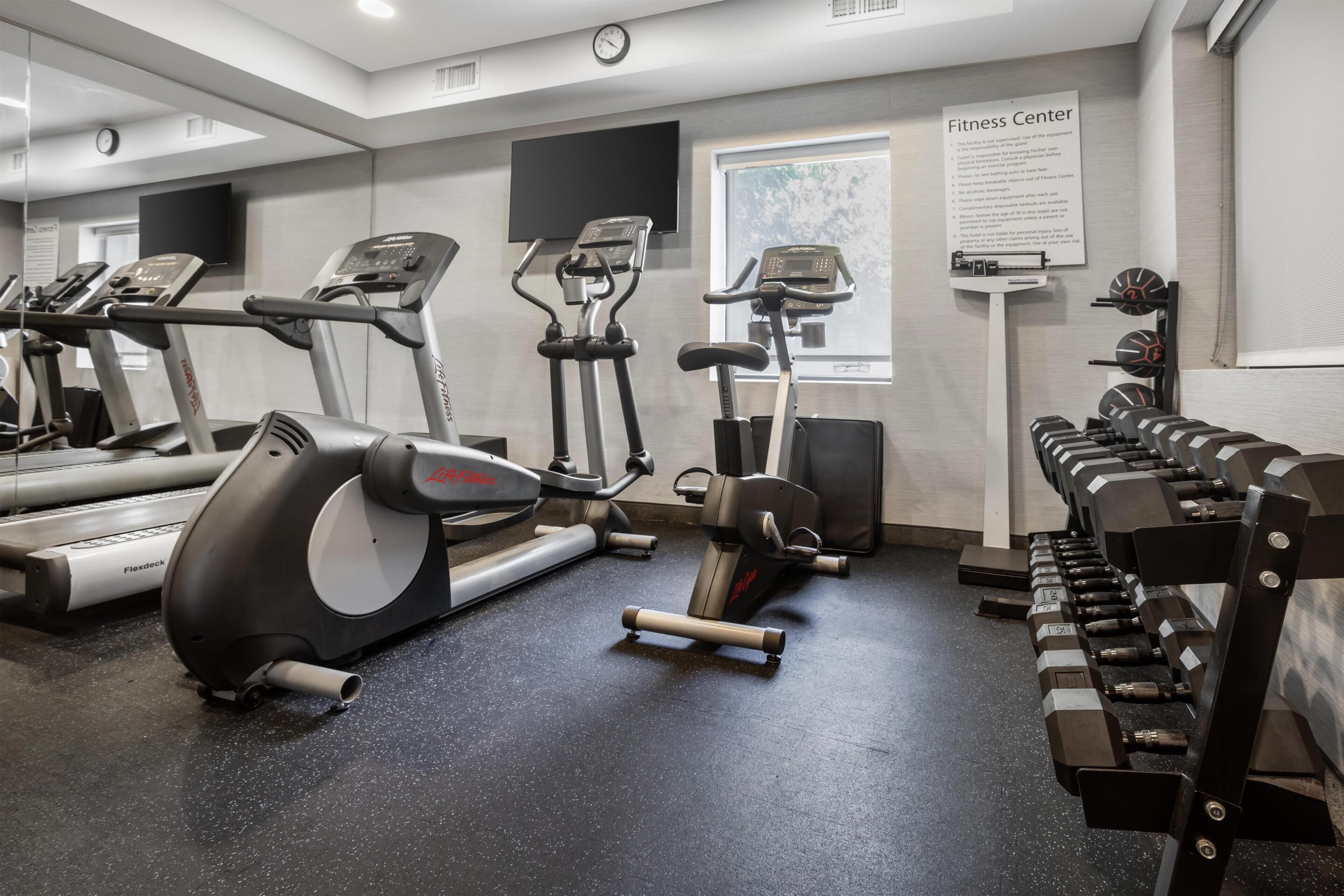 Un centre de remise en forme équipé de tapis de course, de vélos elliptiques et d’une zone dédiée aux exercices de musculation.