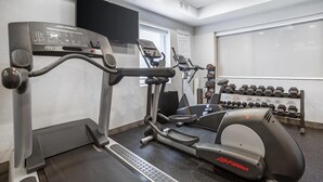 A fitness center with treadmills, elliptical machines, and a wall-mounted TV.