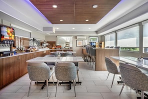 A modern dining area with a bar, seating, and a view of the outdoors.