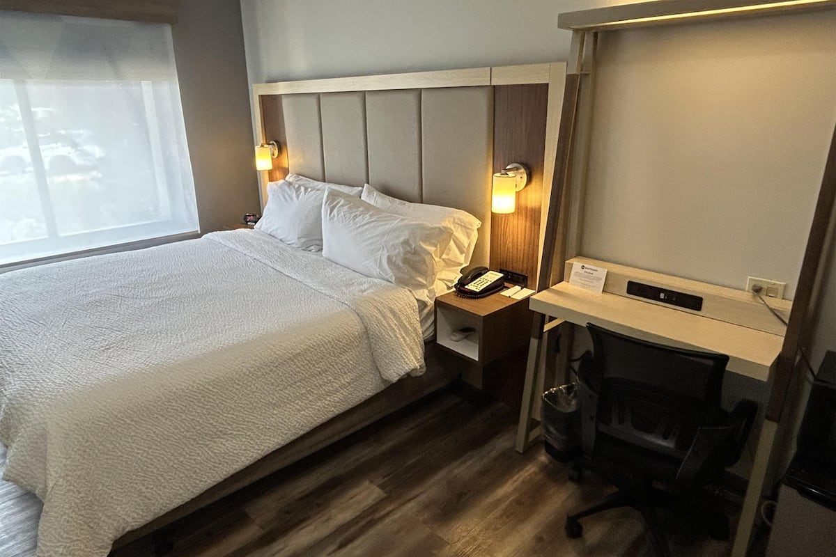 Une chambre d’hôtel avec un grand lit, un bureau, une chaise et un téléphone.