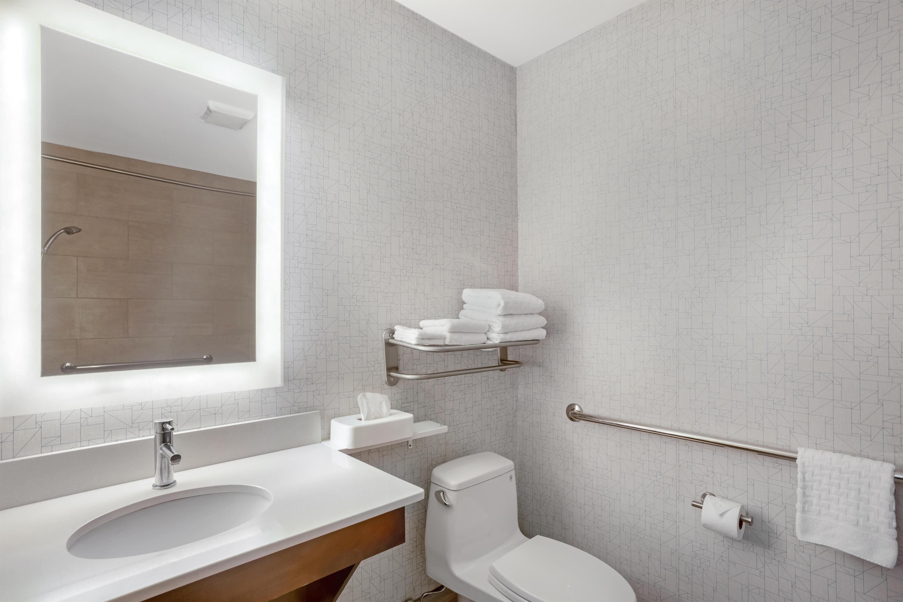 Een moderne badkamer met een wastafel, spiegel, toilet, handdoekhouder en douche.