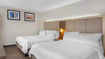A hotel room with two beds, a nightstand, and a wall-mounted lamp.