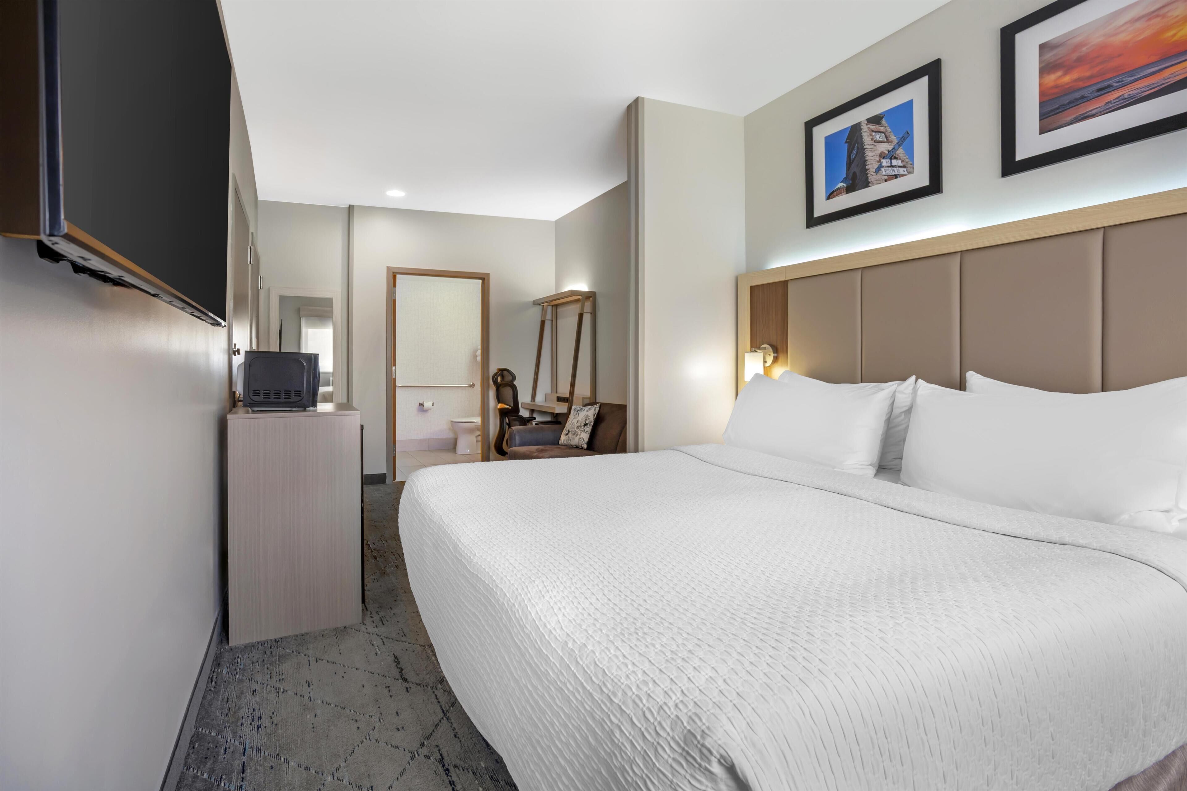 A hotel room with a large bed, a television, a desk, and a bathroom.