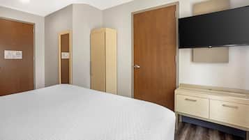 A hotel room with a bed, wardrobe, and a TV mounted on the wall.