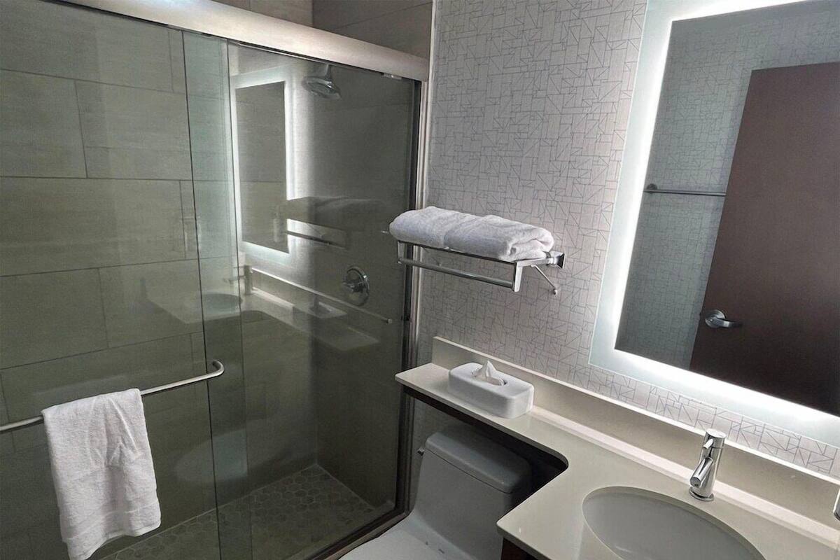 Une salle de bain moderne avec une douche à parois de verre, des toilettes, un lavabo et un porte-serviettes.