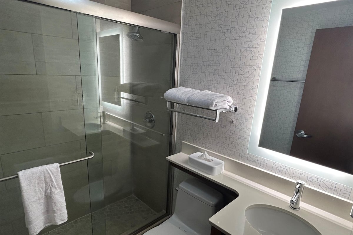Une salle de bain moderne avec une douche à parois de verre, des toilettes, un lavabo et un porte-serviettes.