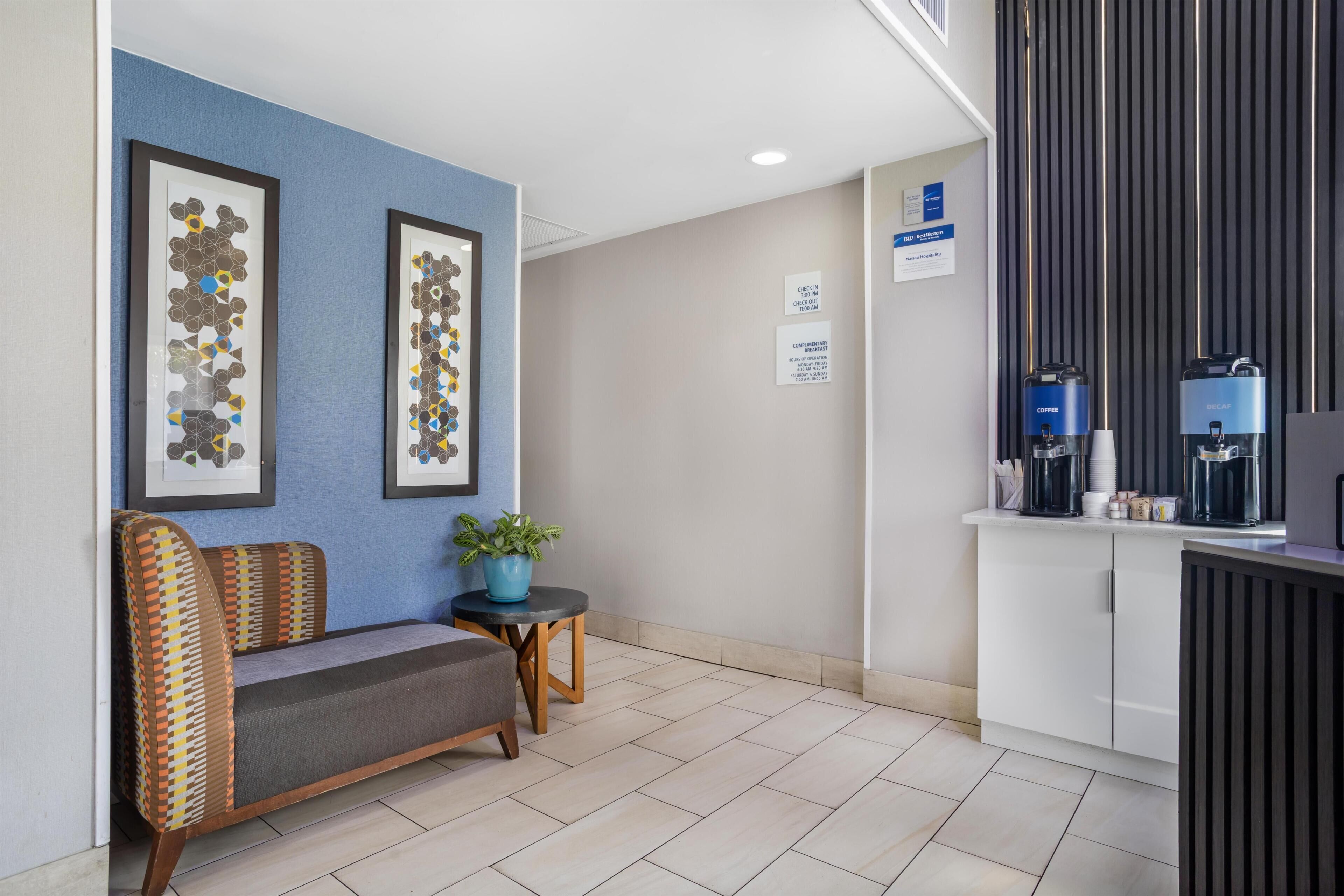 En hotellobby med reception, siddeområde og indrammede kunstværker på væggen.