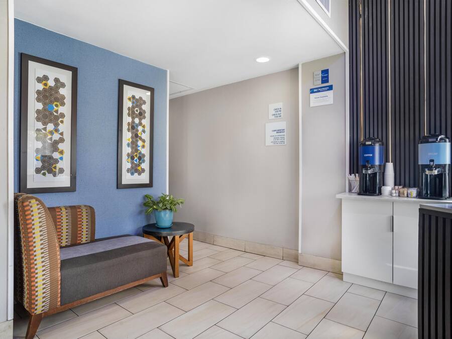 A hotel lobby with a reception desk, seating area, and framed artwork on the wall.