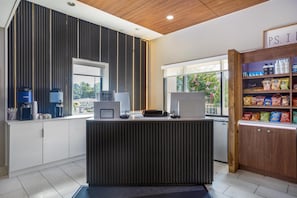 A reception desk with a coffee machine, a computer, and a sign welcoming guests.