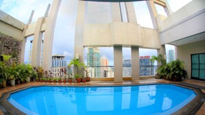 A swimming pool with a view of tall buildings in the background. - BSA Suites Makati (Makati)