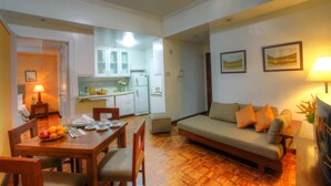 A compact living space with a dining area, kitchenette, and a sofa with cushions. - BSA Tower Serviced Residences (Makati)