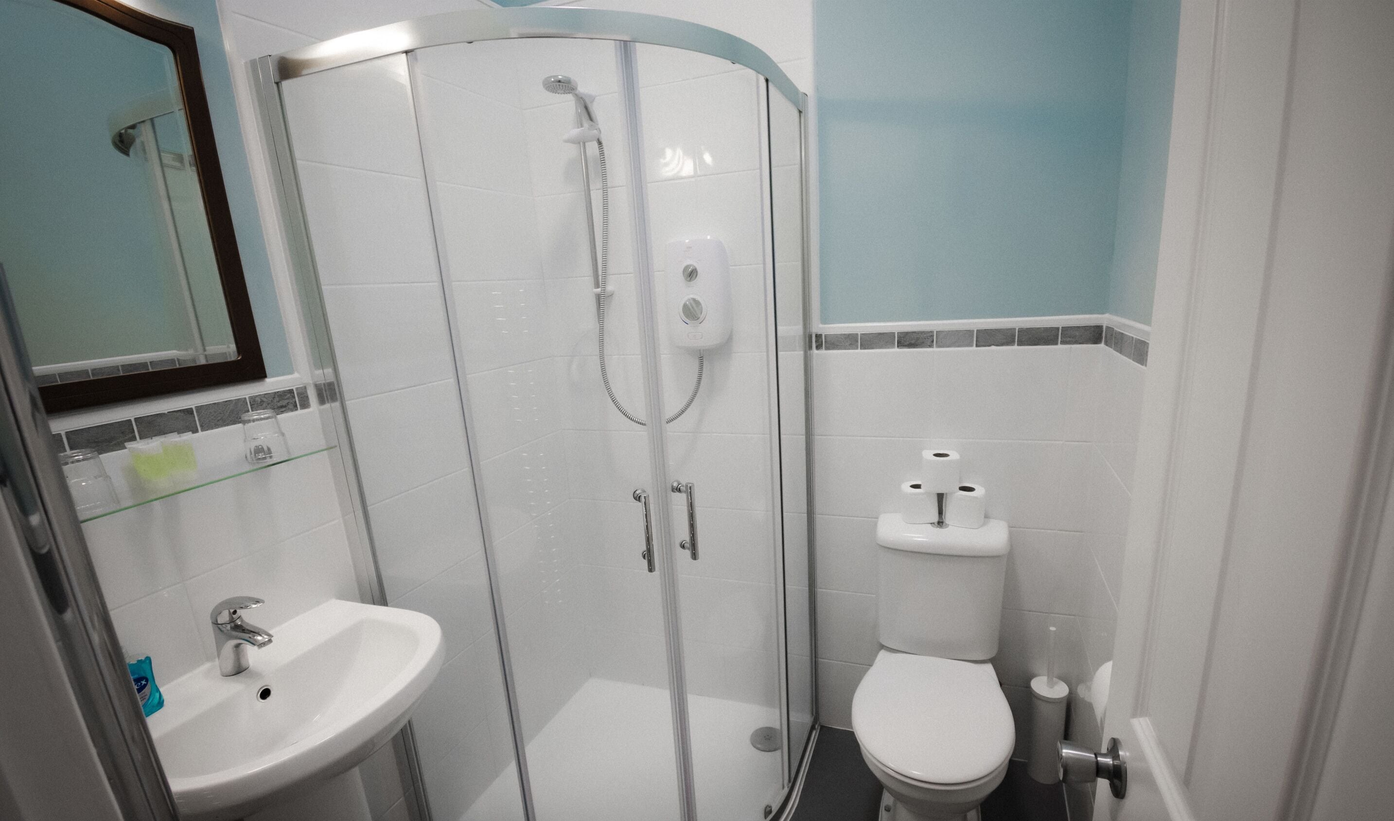 A bathroom with a glass-enclosed shower, a sink, and a toilet.
