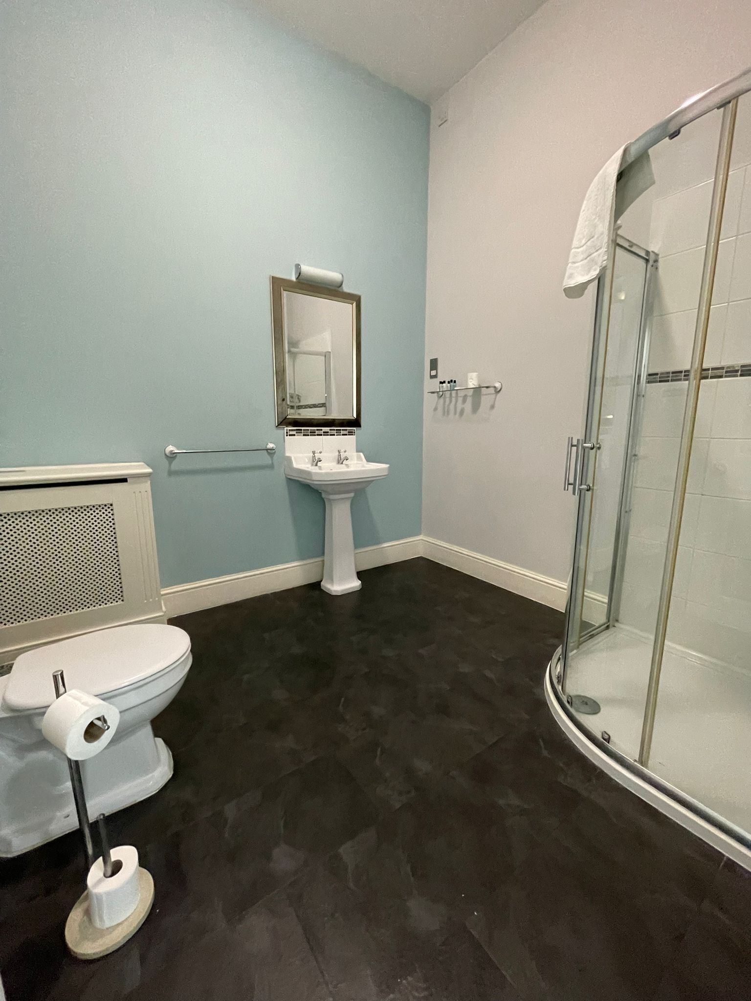 A bathroom with a toilet, sink, and glass shower enclosure.