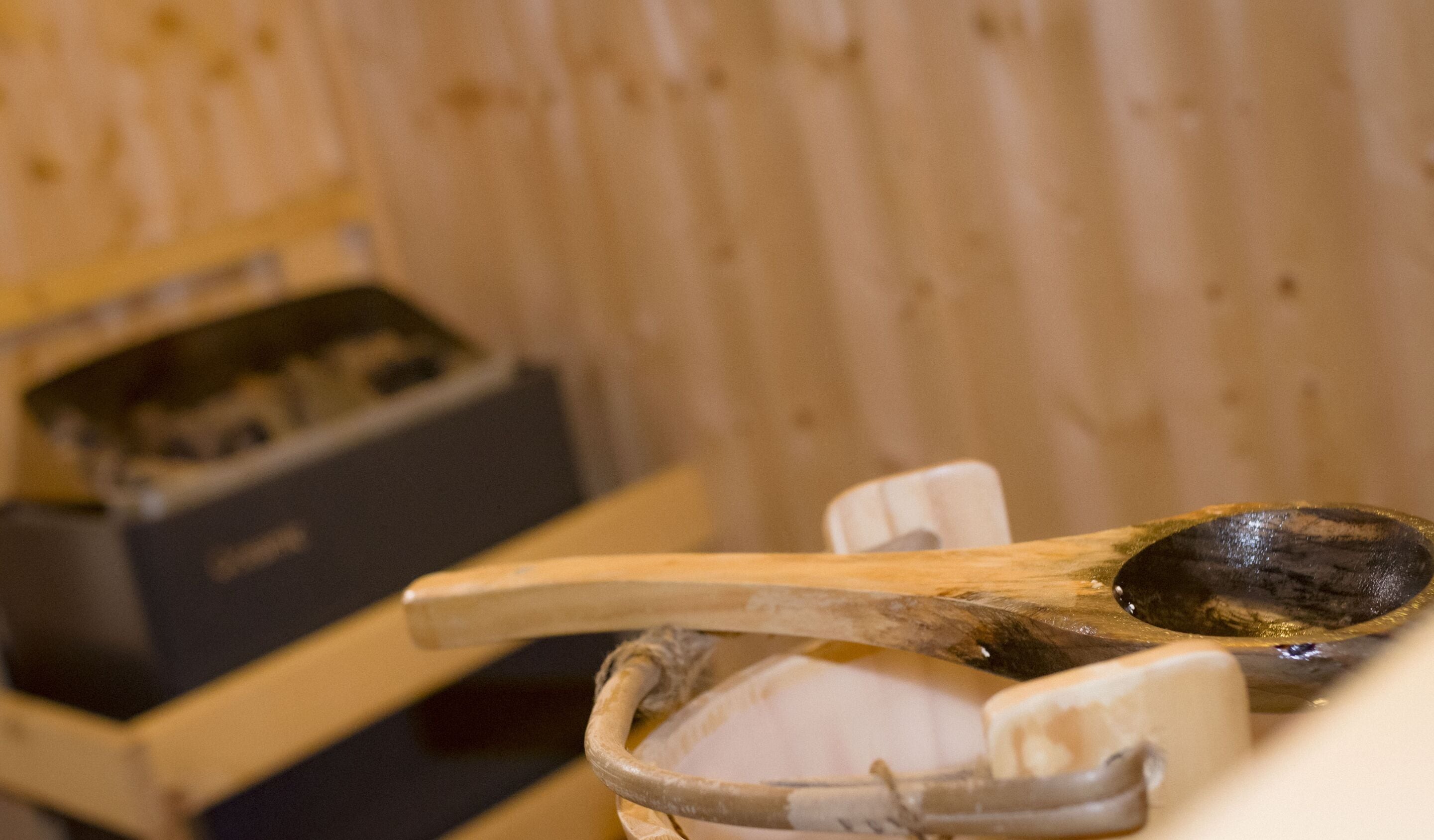 Une cuillère en bois posée sur un bol en céramique blanche, avec une boîte en bois en arrière-plan.