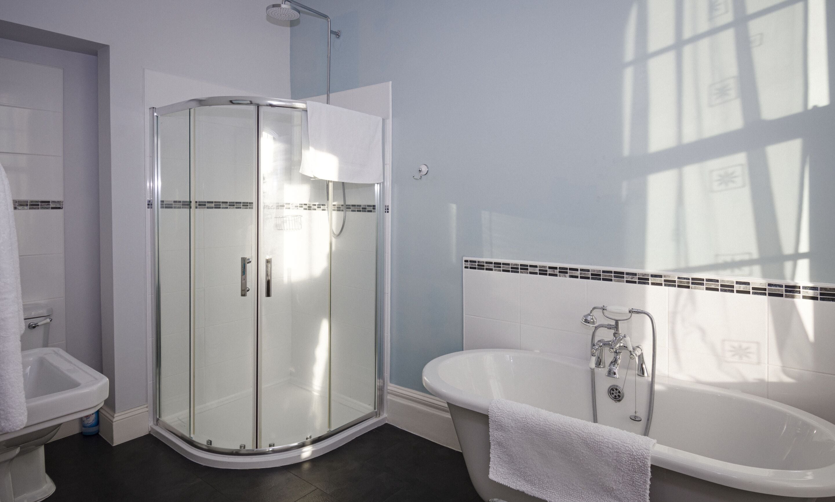 A bathroom with a glass-enclosed shower, a white bathtub, and a toilet.