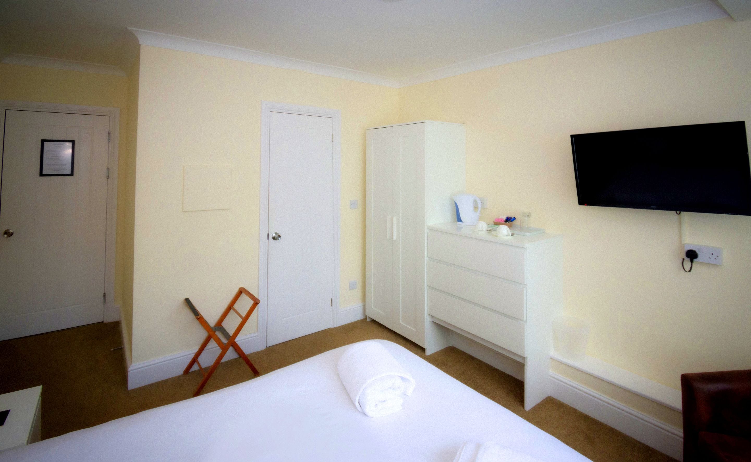A hotel room with a bed, a wardrobe, a television, and a desk.