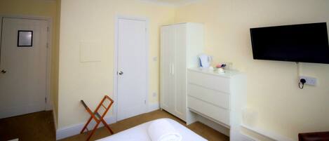 A hotel room with a bed, a wardrobe, a television, and a desk.