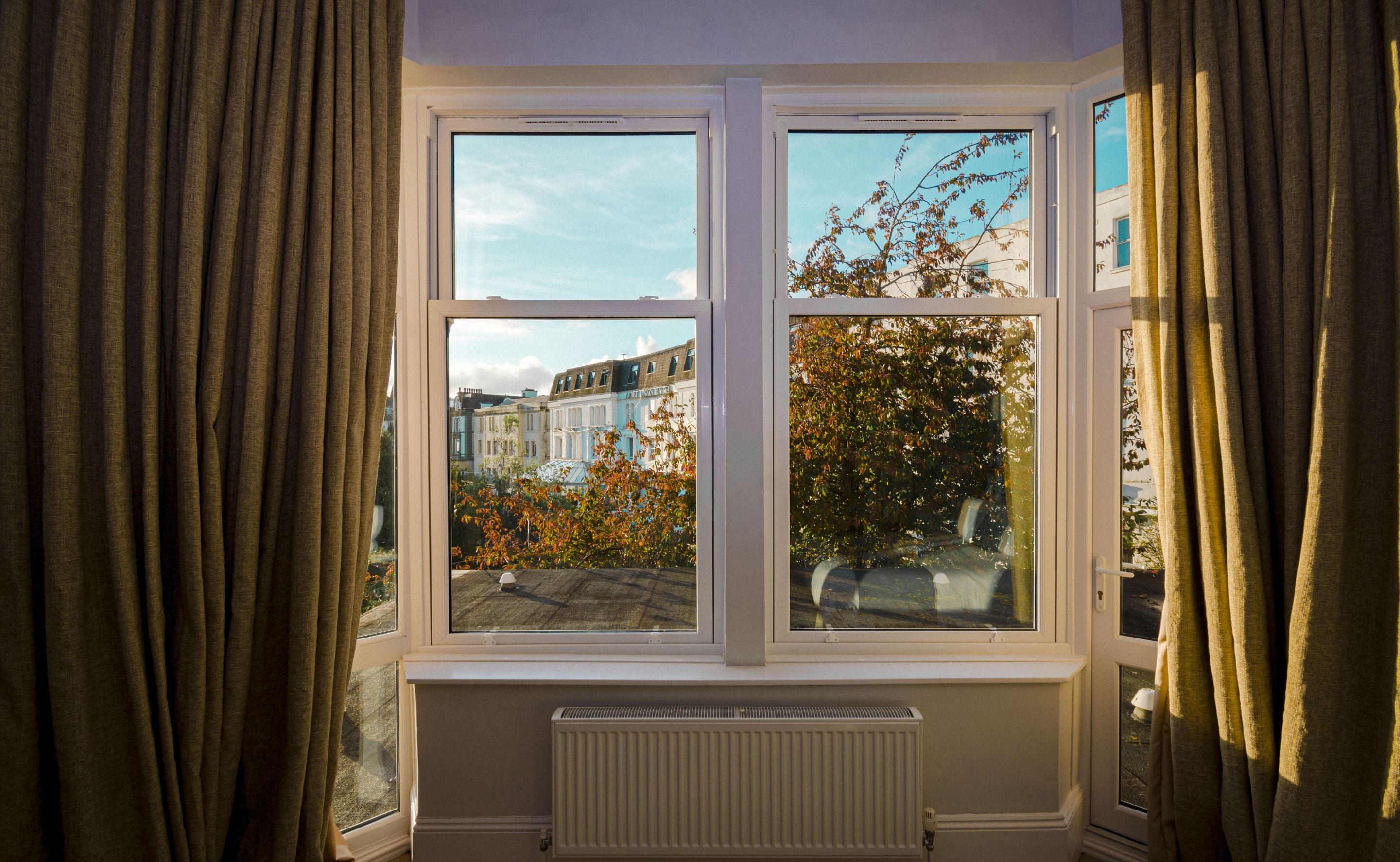 A room with a large window, white radiator, and curtains.