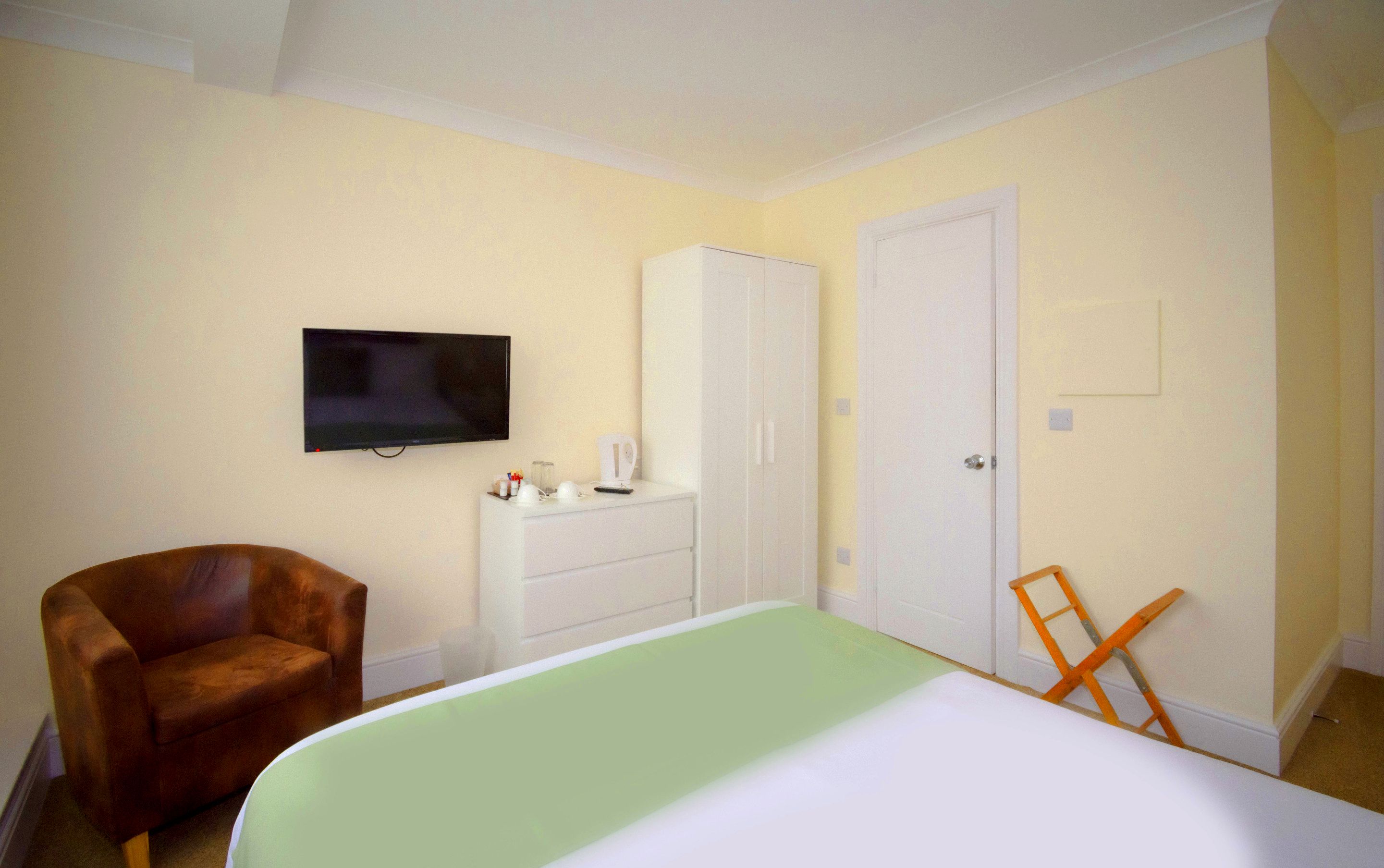 Un dormitorio con cama, televisión, armario y silla.