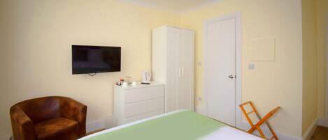 Un dormitorio con cama, televisión, armario y silla.