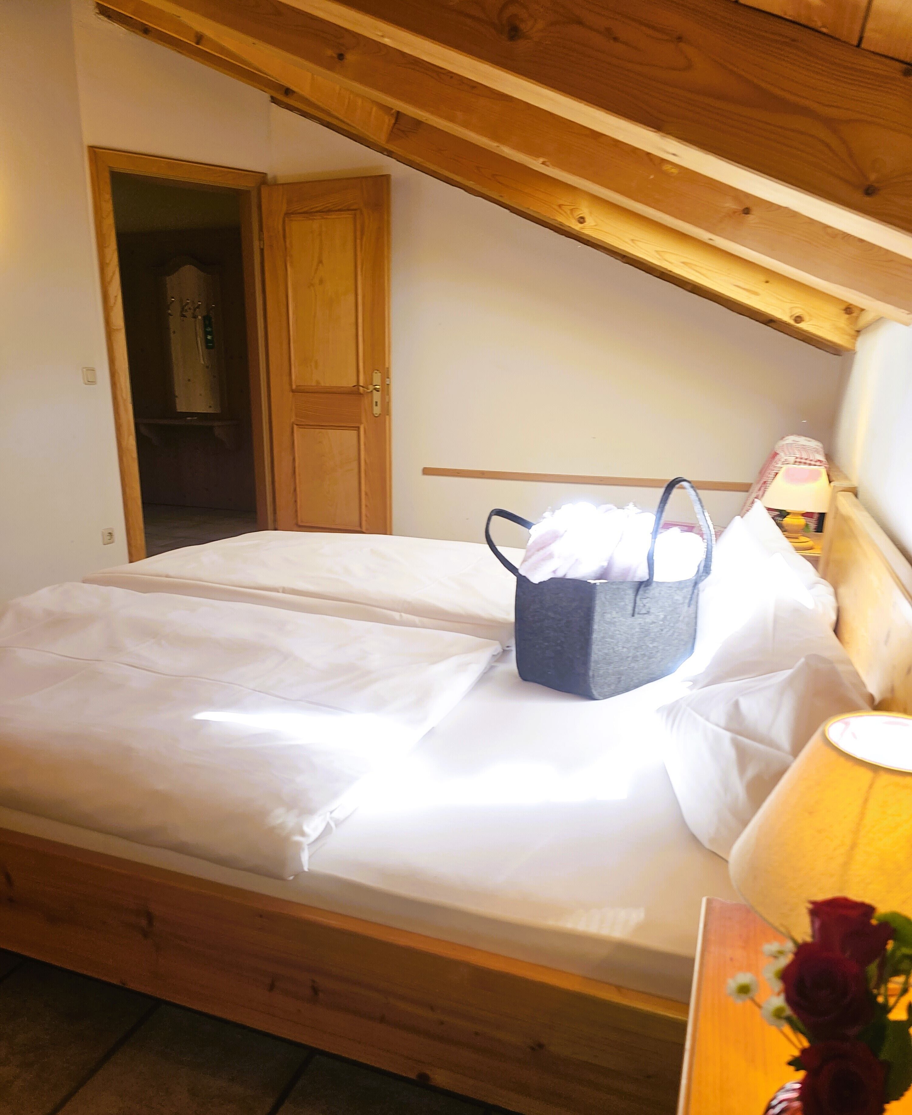 A single bed with a wooden headboard, a bedside table with a lamp, and a small basket on the bed.