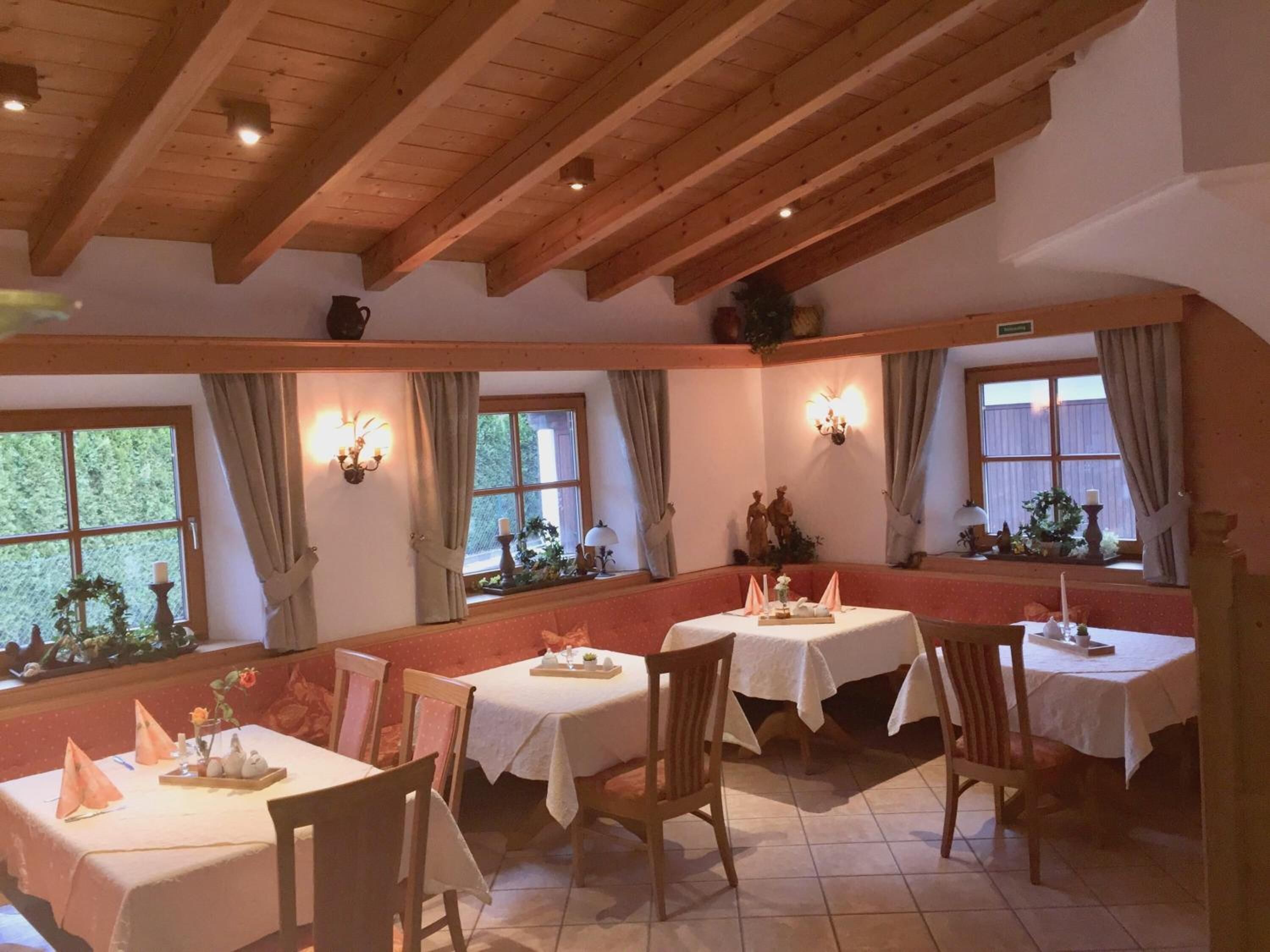 Comedor con vigas de madera, manteles blancos y un ambiente cálido a la luz de las velas.