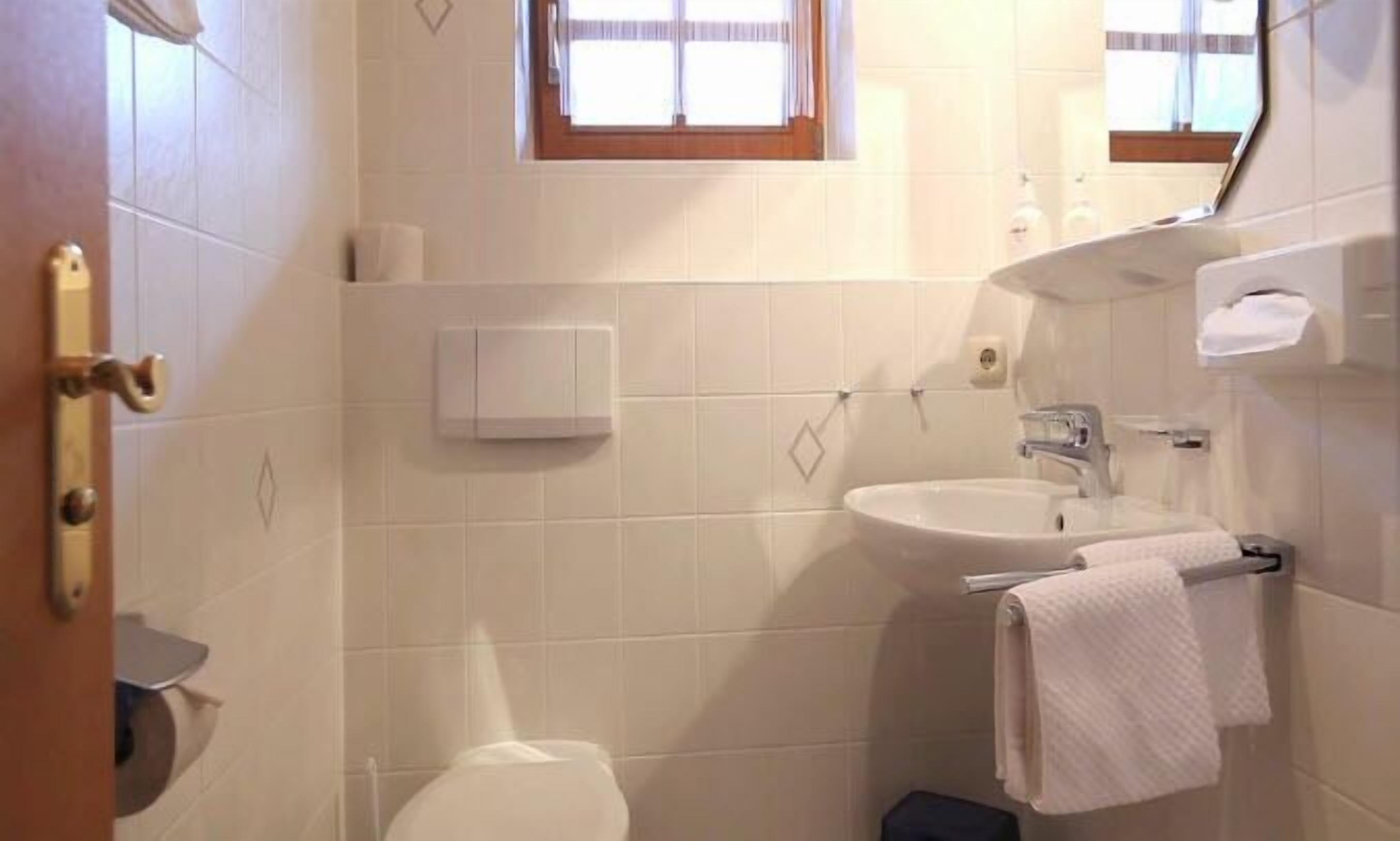 Un baño con inodoro, lavamanos y ventana.
