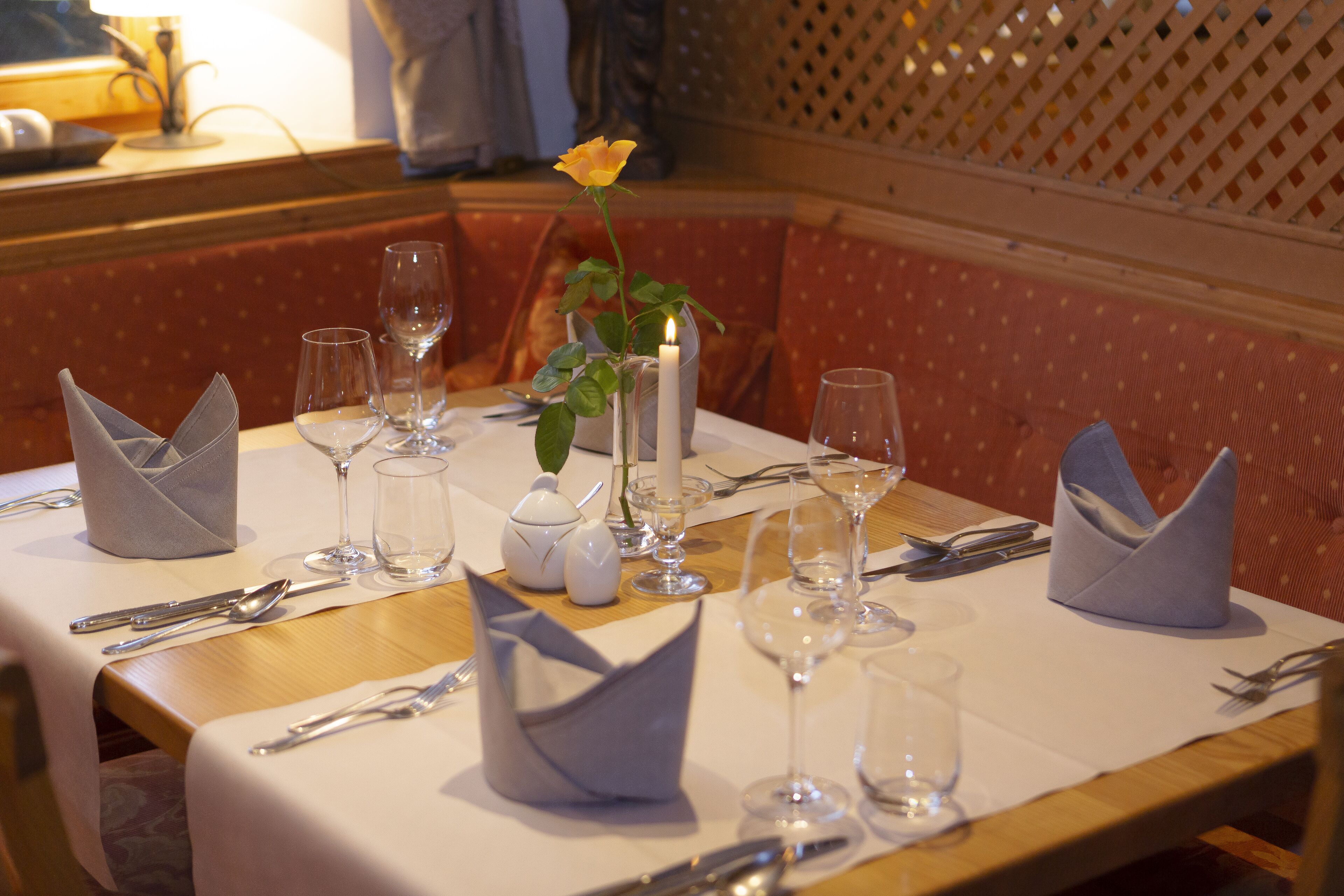 A dining table set with white tablecloth, silverware, and clear wine glasses.