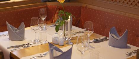 A dining table set with white tablecloth, silverware, and clear wine glasses.