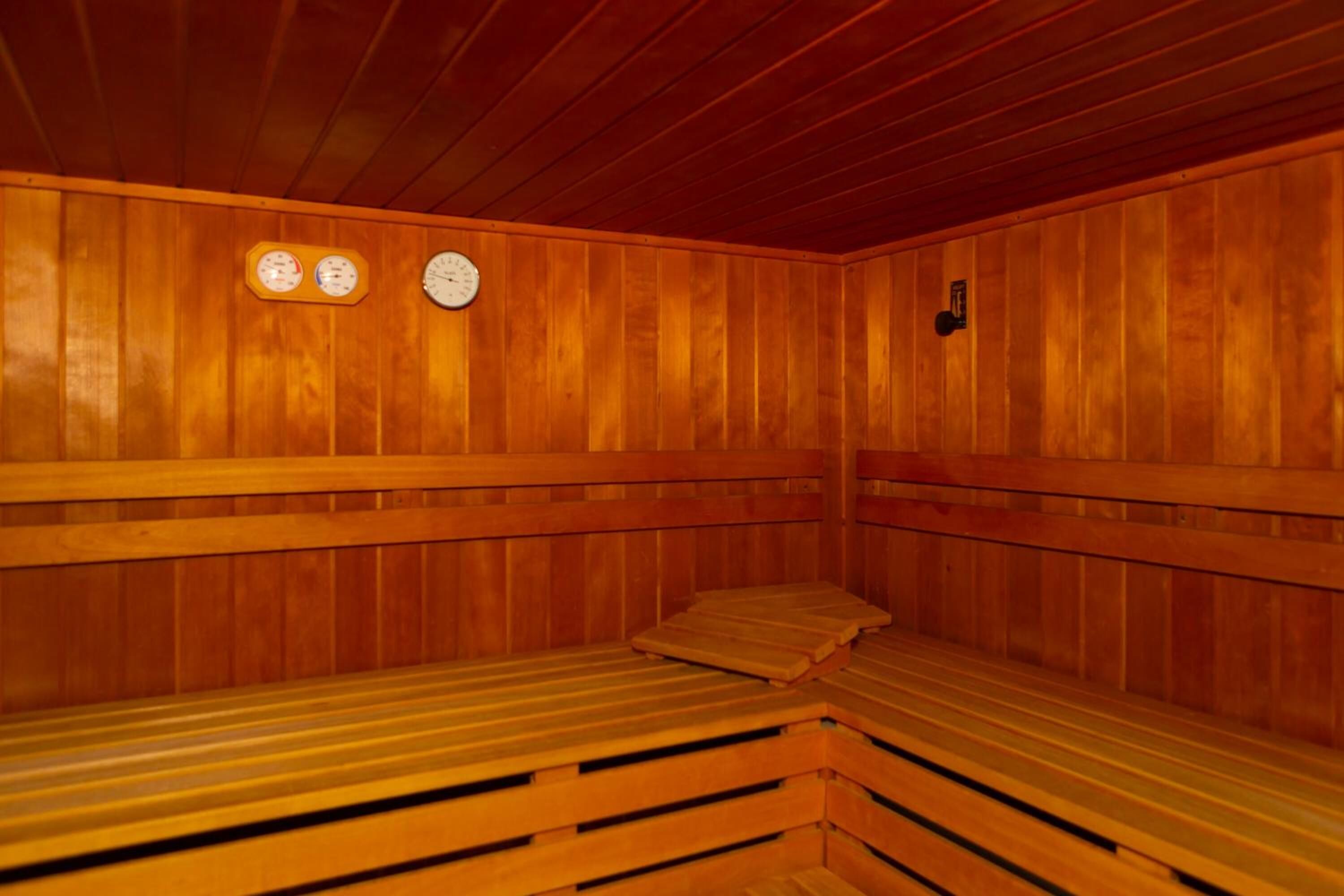 Una sauna con bancos de madera y dos relojes en la pared.