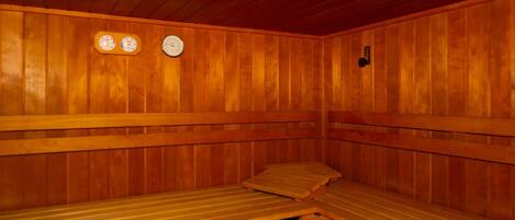 A sauna room with wooden benches and two wall-mounted clocks.