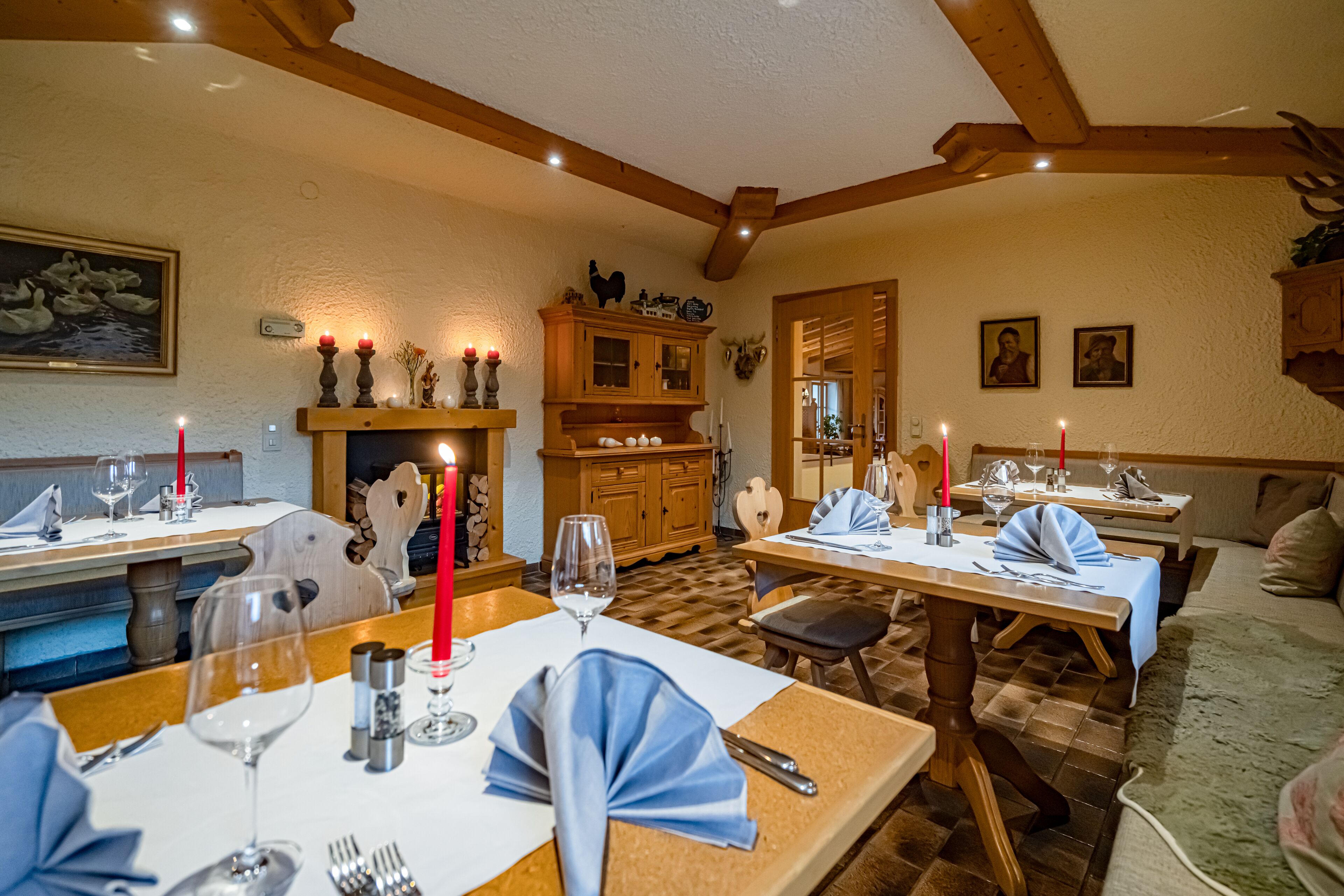 A dining area with wooden tables, candles, and a fireplace.