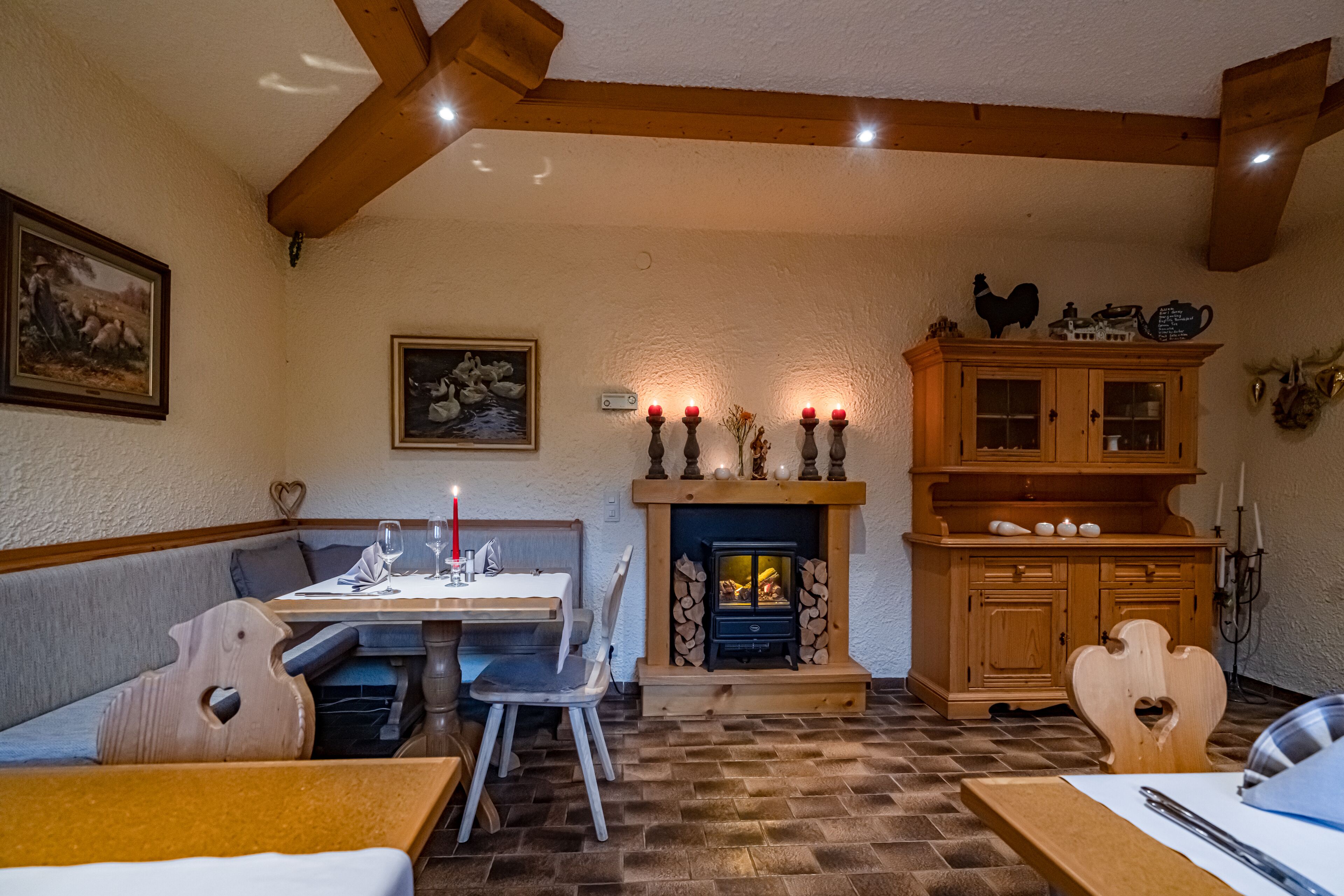 A cozy dining area with a fireplace, wooden furniture, and a table set for two.