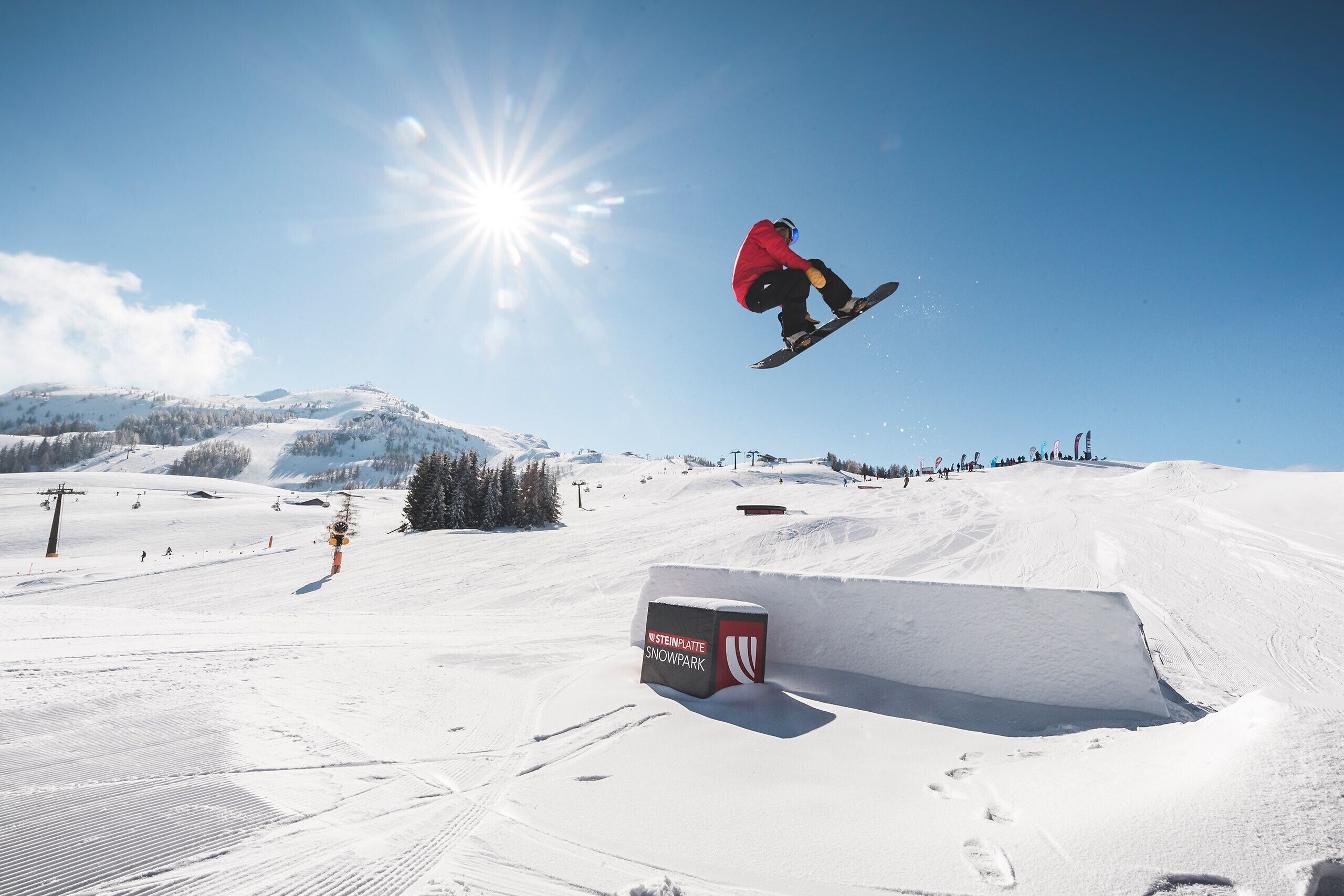 A snowboarder performing a jump at a snow park.