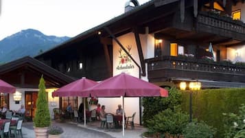 A hotel with outdoor seating and a mountain backdrop.