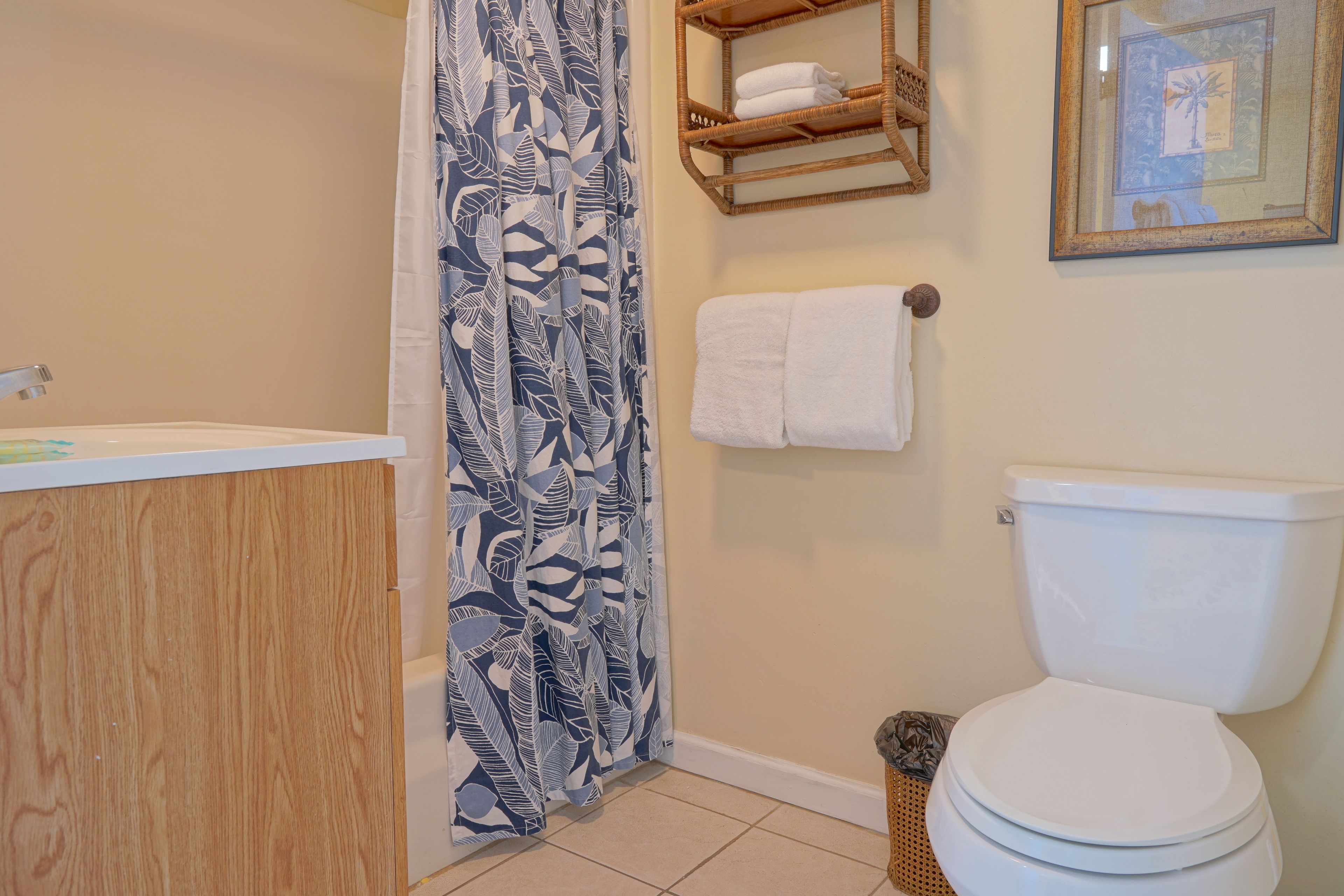 A bathroom with a shower curtain, a toilet, a sink, and a towel rack.