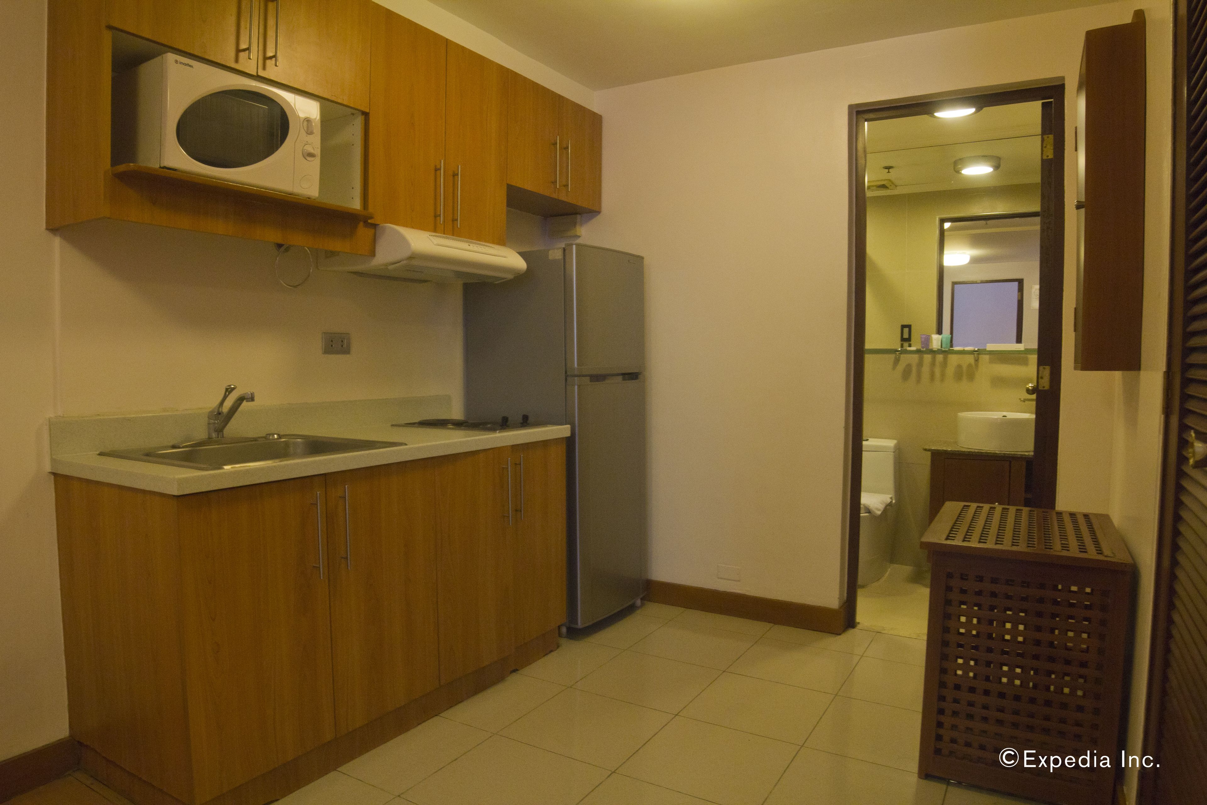 Una cocina compacta con armarios de madera, un refrigerador de acero inoxidable y un microondas.