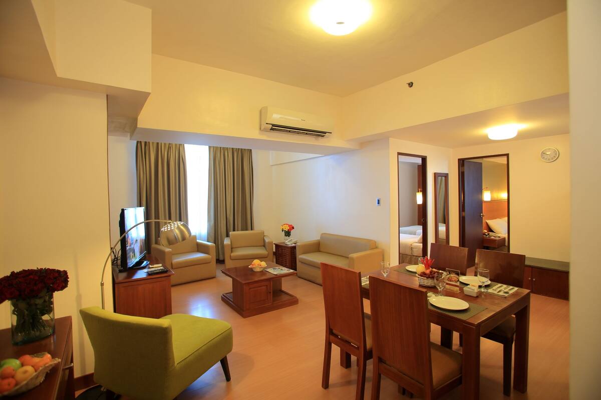 Habitación de hotel con sala de estar, mesa de comedor y cama.