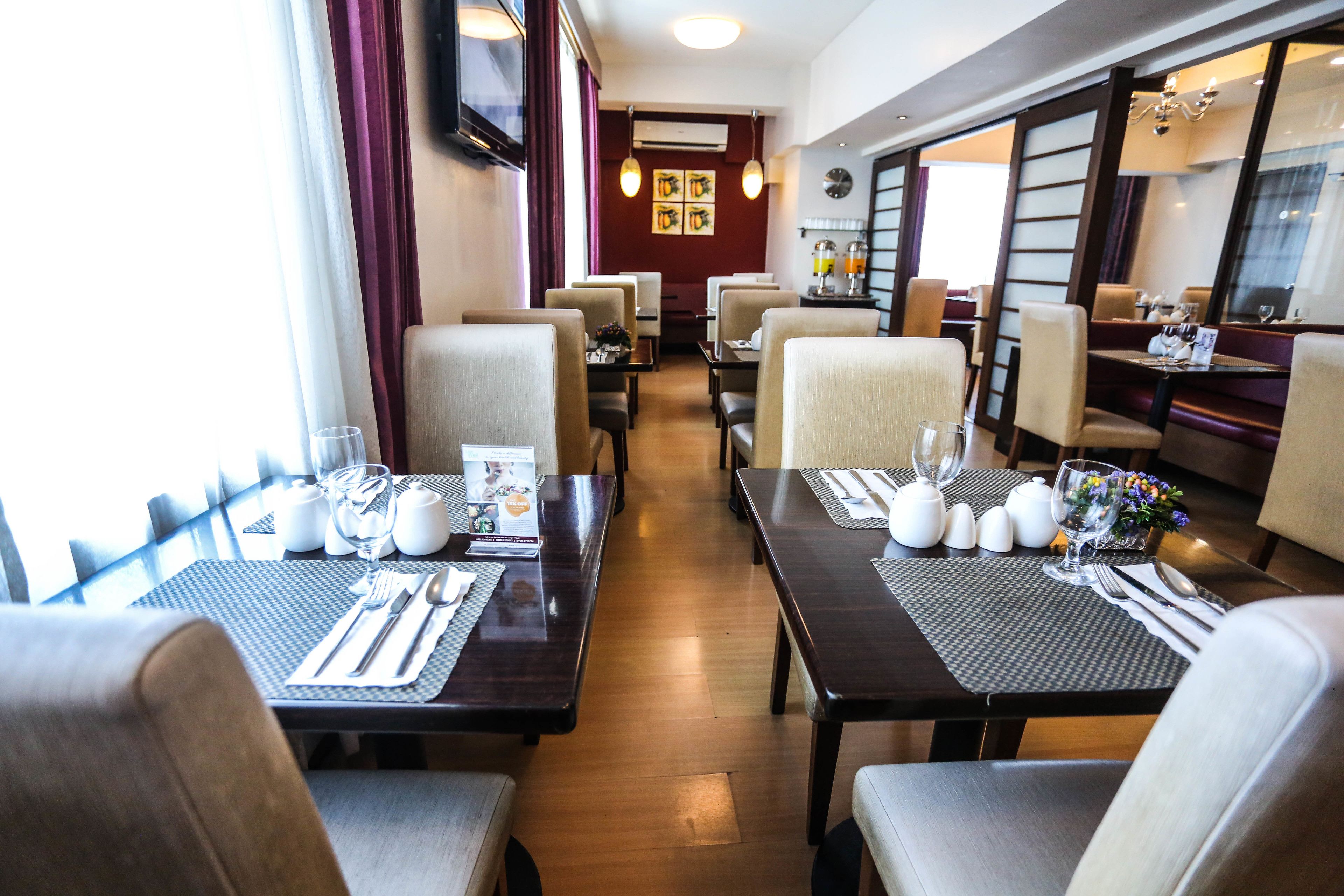 A restaurant with tables set for dining, chairs, and a bar area.