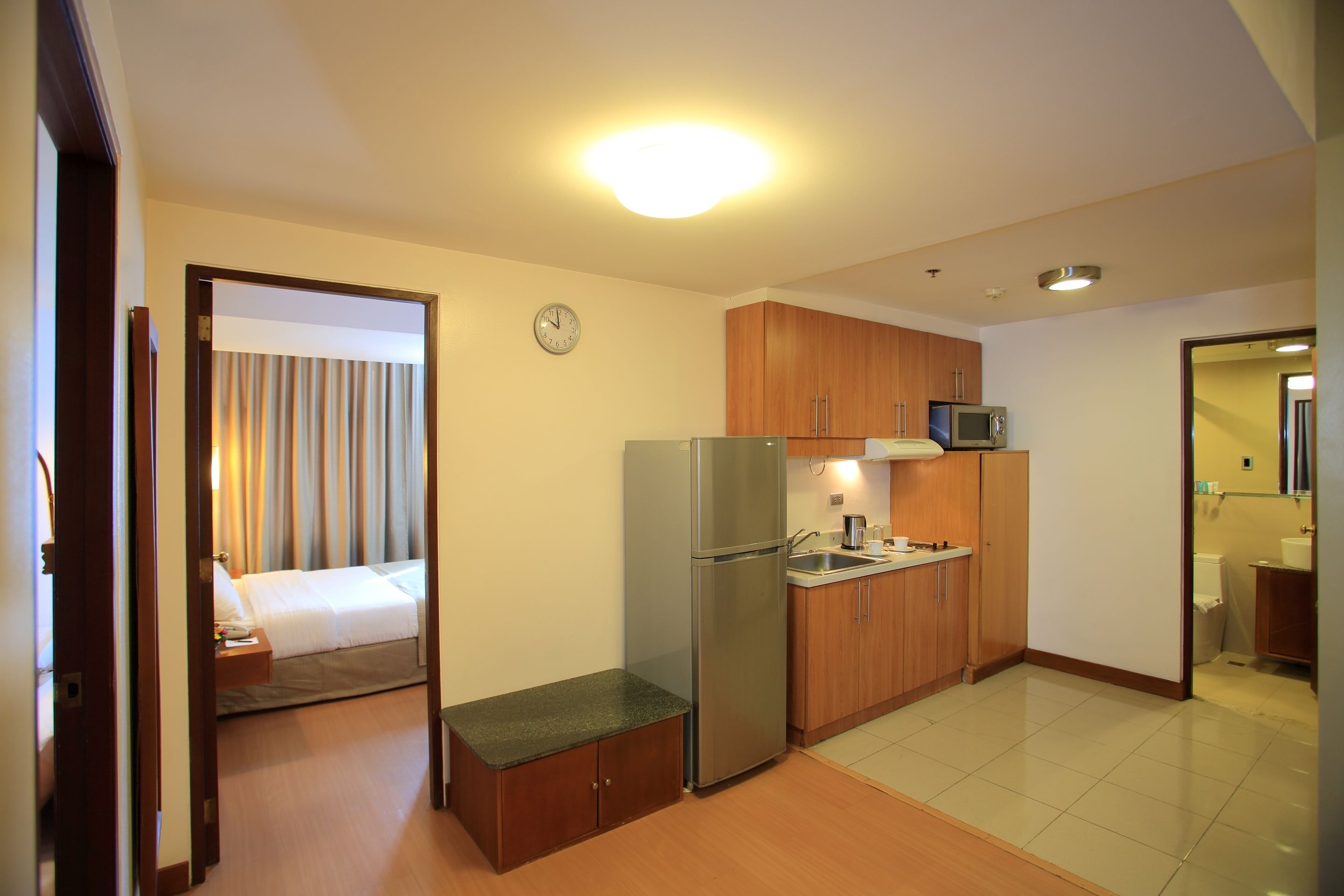 A compact hotel room with a kitchenette, a bed, and a bathroom.