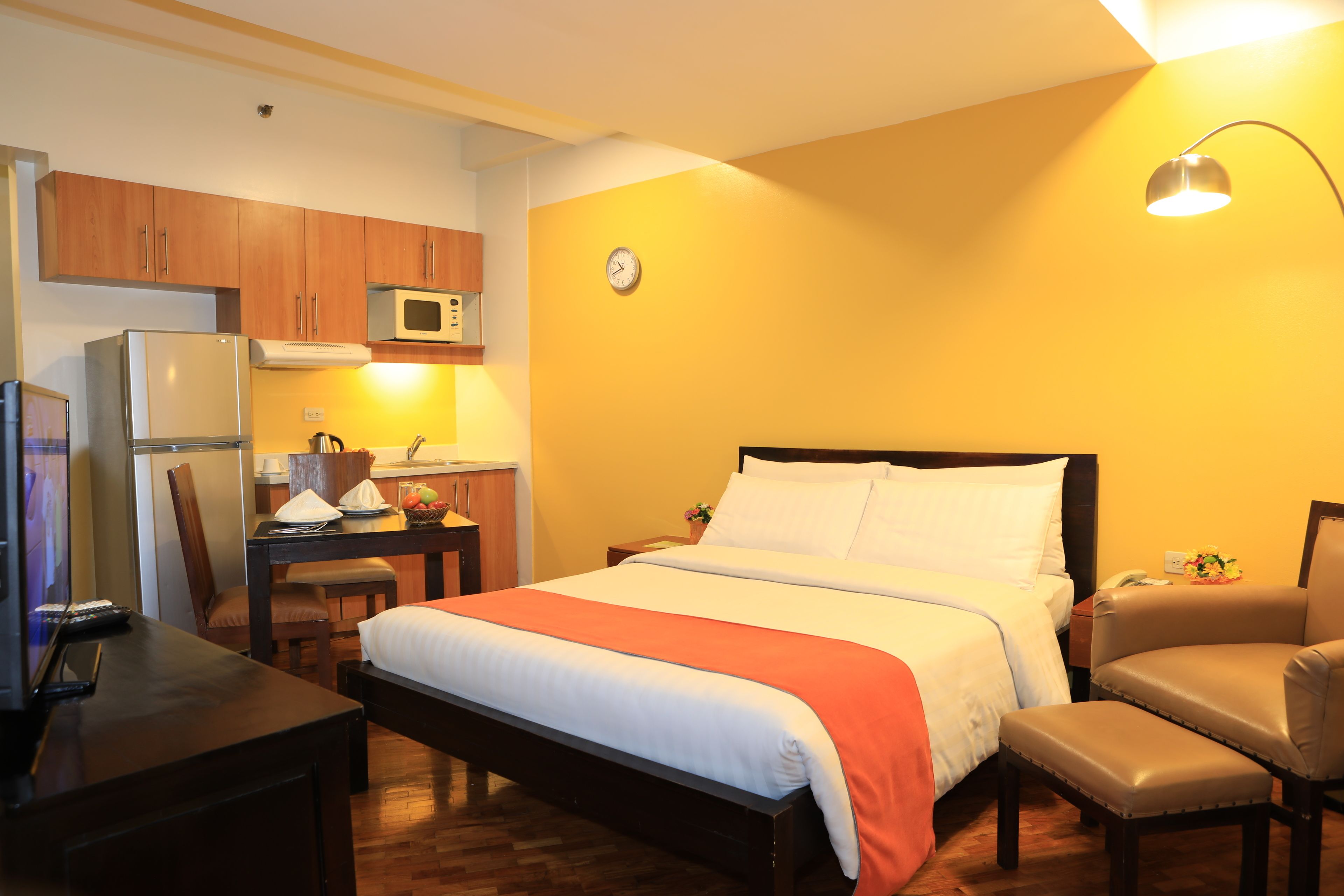 Een kleine hotelkamer met een bed, een bureau, een stoel, een magnetron en een koelkast.