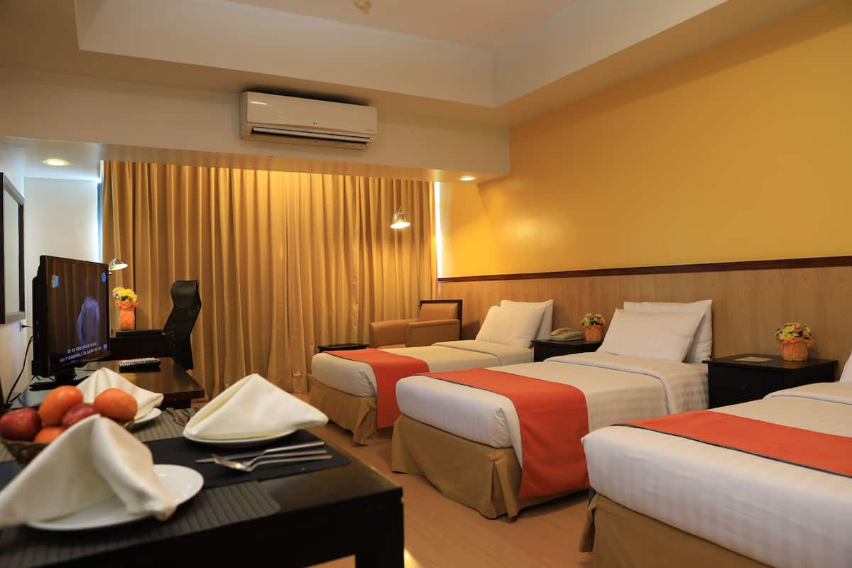 Habitación de hotel con dos camas, un escritorio con computadora, televisión y una silla.